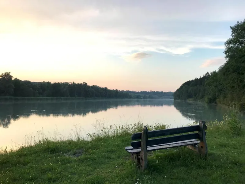 Bank am Ufer des Inn in der Abenddämmerung